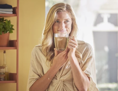 Blonde vrouw die thee uit een glazen Pickwick glas drinkt.